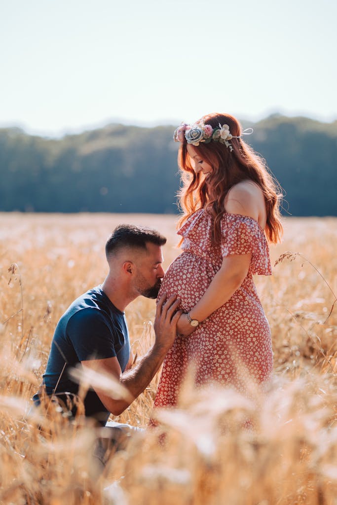 Boho themed maternity photoshoot in wheatfield - Kissing baby bump