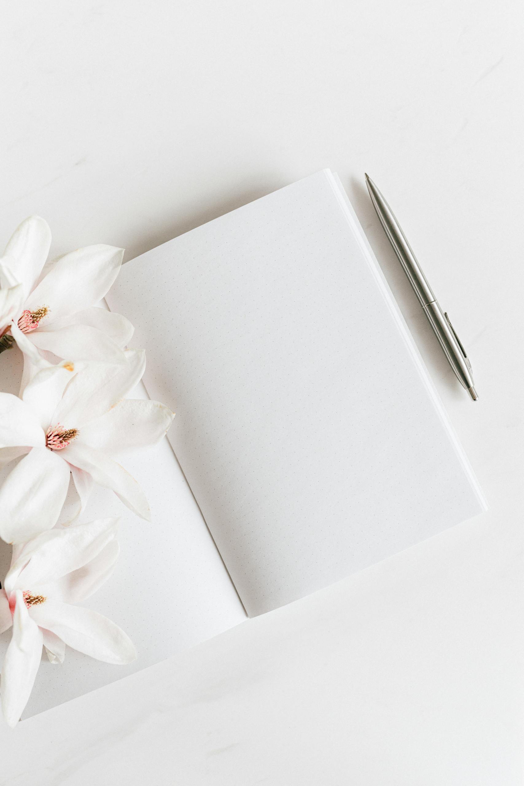 Opened notebook with silver pen near Magnolia